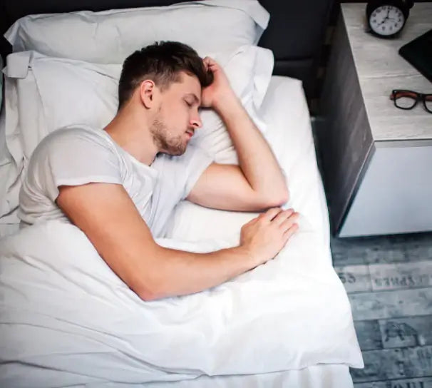 White man with brown hair sleeping peacefully in his bed