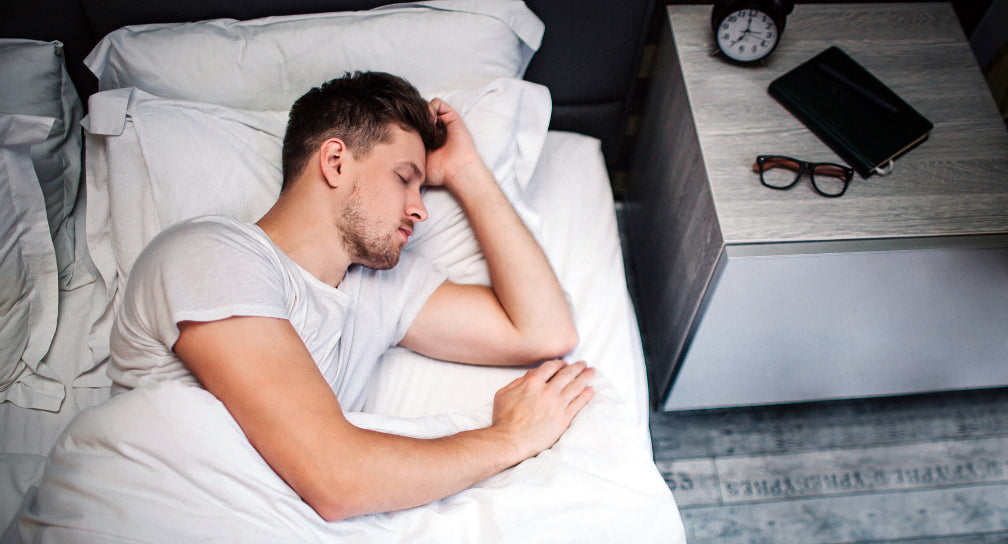 White man with brown hair sleeping peacefully in his bed